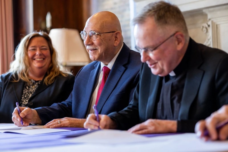 President Ray DiPasquale (center) signs transfer agreement between Massasoit and Stonehill College