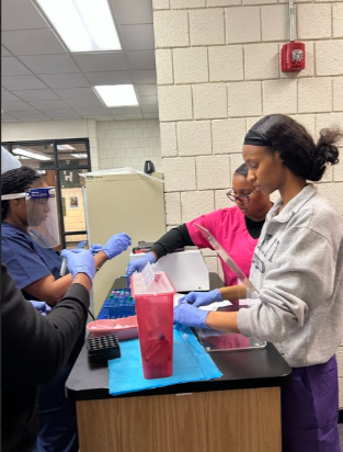 Phlebotomy Tech students working on their lab skills in a classroom.