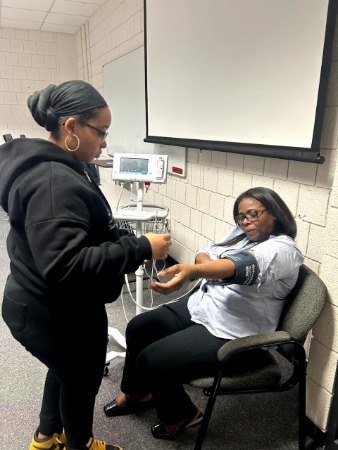 Two students practicing taking blood pressure.