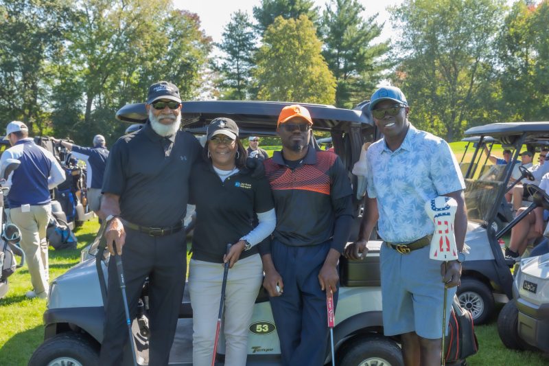 Group of people smiling standing at a golf course.